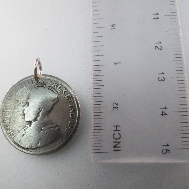 May include: Silver coin pendant with a profile of a woman wearing a crown and the text "GEORGIVS V DEI GRA REX ET IND IMP" around the edge. The coin is about 1 1/2 inches in diameter.