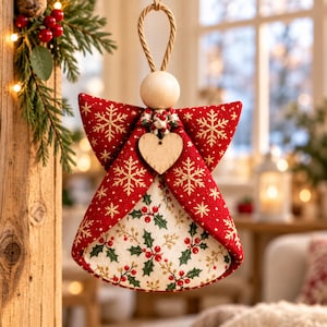 May include: A hanging angel ornament featuring a red fabric body with gold snowflake patterns and a cream-colored skirt printed with green holly leaves and red berries. The figure has a plain wooden bead head and a small wooden heart at the neck.