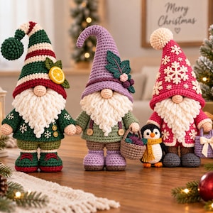 Puede incluir: Tres figuras de gnomos de ganchillo y una pequeña figura de pingüino. El primer gnomo lleva un gorro a rayas verdes y rojas con una rodaja de limón. El segundo gnomo lleva un gorro lavanda con hojas y lleva una cesta. El tercer gnomo lleva un gorro rosa con copos de nieve blancos y lleva un pequeño bolso.
