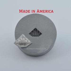 May include: A metal die with a fan-shaped design, accompanied by a matching stamped piece. The die is circular and has a recessed fan shape. The stamped piece is a smaller, detailed version of the design. Text reads "MADE IN AMERICA".