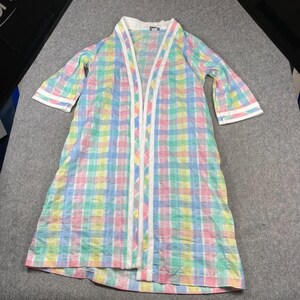 May include: A long-sleeved open-front robe featuring a pastel plaid pattern in shades of pink, yellow, blue, and green. The garment includes a solid white trim along the collar, down the front opening, and at the ends of the three-quarter length sleeves.