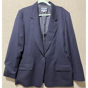 May include: A navy blue blazer with a single-button closure and two front pockets. The blazer has a notched lapel and is hanging on a light green hanger. The brand name "Pendleton" is visible on the label.