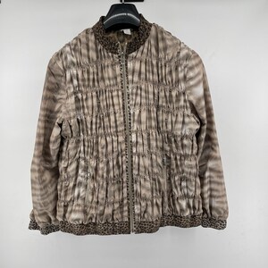 May include: A tan and brown ruched jacket with a full zipper closure. The jacket has a round collar and cuffs with a leopard print design. The jacket is hanging on a black hanger.