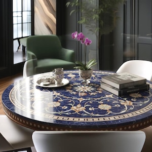 Pu&ograve; includere: Un tavolo rotondo con una superficie blu scuro con un motivo floreale bianco e oro. Il tavolo ha un bordo in legno ed &egrave; circondato da sedie bianche. Un vaso di orchidee viola e libri sono sul tavolo.