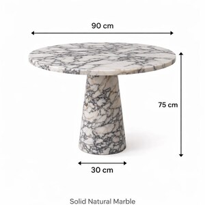 May include: A round marble table with a white and gray pattern. The tabletop is 35 inches in diameter and the table is 29.5 inches tall. The base is 12 inches wide. The text "Solid Natural Marble" is at the bottom.