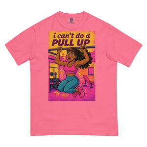 Pode incluir: T-shirt rosa com um desenho de uma mulher a tentar fazer uma barra fixa, com o texto "i can't do a PULL UP". A mulher usa um soutien desportivo rosa e leggings turquesas. No fundo, vê-se equipamento de ginásio.