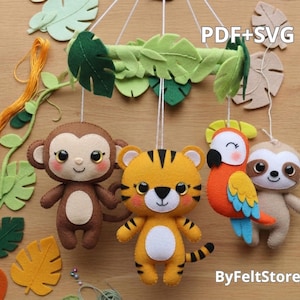 Può includere: Mobile per bambini fatto a mano in feltro con una scimmia, una tigre, un pappagallo e un bradipo. Il mobile include foglie verdi in feltro e un ramo, con il testo "PDF+SVG" e "ByFeltStore". Gli animali sono marroni, gialli, arancioni e beige.