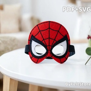 May include: A red felt mask with a black spiderweb pattern and white eye cutouts outlined in black. The mask features a black elastic strap on each side. The text PDF+SVG and ByFeltStore are visible in the image.
