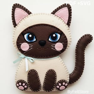 Può includere: Un gatto siamese in feltro fatto a mano con corpo color crema, muso e coda marroni e orecchie interne rosa. Il gatto ha grandi occhi blu, guance rosa e un nastro azzurro. Il disegno è cucito con filo bianco. I testi "PDF + SVG" e "ByFeltStore" sono visibili.