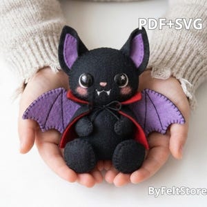 May include: A black felt bat plush toy with purple inner ears and wings, wearing a red-lined cape with a black tie. The bat has large black eyes, a small pink nose, and two white fangs. The text PDF+SVG and ByFeltStore are visible.