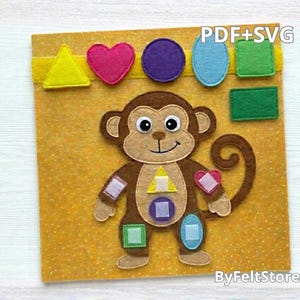 Pode incluir: Um brinquedo educativo de feltro com um macaco castanho com várias formas coloridas. O macaco tem formas no corpo, e formas adicionais são presas no topo. O fundo é amarelo com o texto "PDF+SVG" e "ByFeltStore".