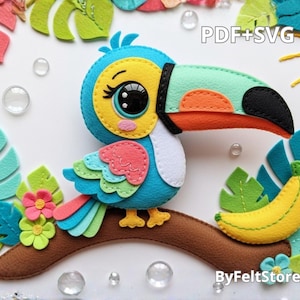 Pode incluir: Um tucano de feltro com um bico grande, empoleirado num galho castanho com uma banana amarela. O tucano é azul, amarelo, laranja e verde, com a ponta do bico preta. O fundo inclui folhas de feltro, flores e o texto "PDF+SVG" e "ByFeltStore".