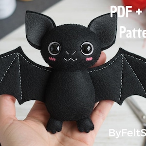 May include: A black felt bat plush toy with large eyes, pink cheeks, and white stitching. The bat has outstretched wings and large ears. The image includes the text "PDF + SVG Pattern" and "ByFeltStore".