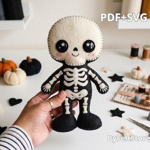 May include: A handmade felt skeleton doll featuring a cream-colored skull with black button eyes, pink cheeks, and a black body with white felt ribcage and bone details. The text PDF+SVG is visible in the upper right corner of the image.