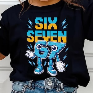 Può includere: T-shirt nera con le parole "SIX SEVEN" in font pixelato giallo e blu. Sotto, i numeri "67" in blu con guanti e scarpe bianche. Grafiche a forma di fulmine su entrambi i lati del testo.
