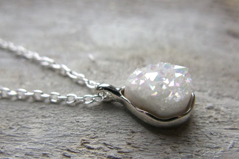 This is a sparkly white druzy necklace. It's a minimalist pendant with some hints of pink when it hits the light. A great present for friends or yourself.