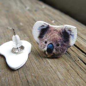 Australian wildlife koala bear stud post earrings, brown and white fuzzy fur with blue noses on wood.