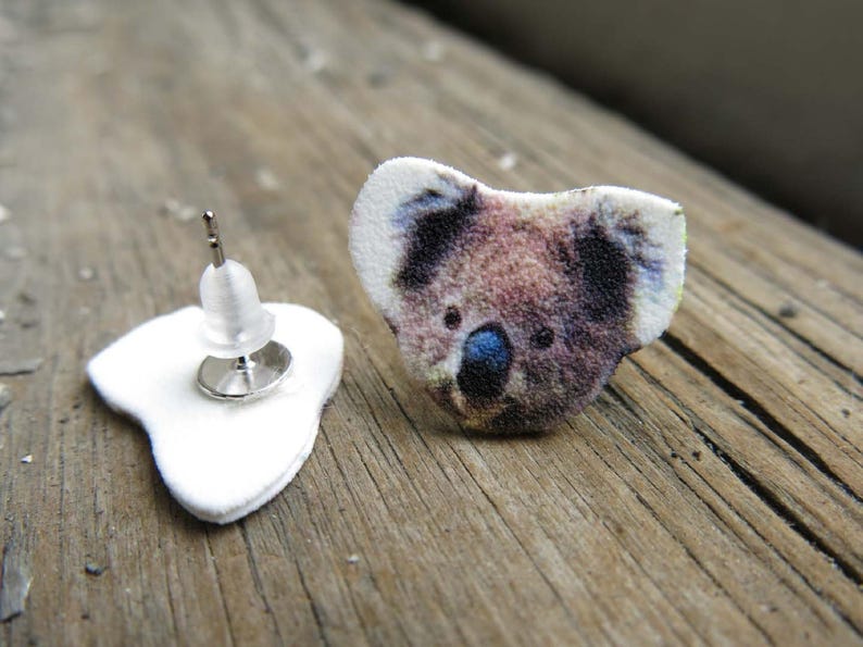 Australian wildlife koala bear stud post earrings, brown and white fuzzy fur with blue noses on wood.