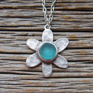 Handmade sea glass flower pendant necklace with aqua blue and other colours in a cabochon in a five-petal silver setting on a silver chain.