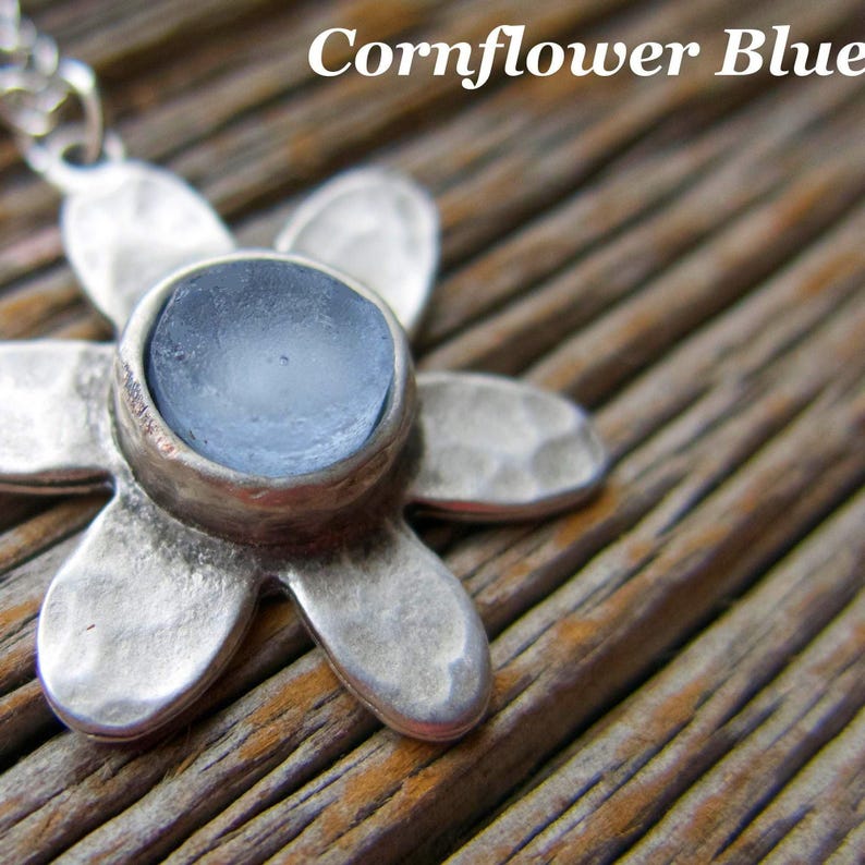 Handmade sea glass flower pendant necklace with aqua blue and other colours in a cabochon in a five-petal silver setting on a silver chain.