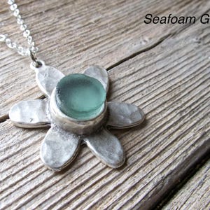Handmade sea glass flower pendant necklace with aqua blue and other colours in a cabochon in a five-petal silver setting on a silver chain.