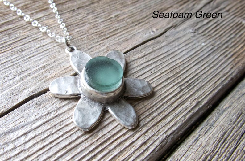 Handmade sea glass flower pendant necklace with aqua blue and other colours in a cabochon in a five-petal silver setting on a silver chain.