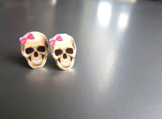 Handmade-in-Canada skull studs with a pink bow twist — gothic-cute done right, and 95 favorites prove people are actually buying this vibe.