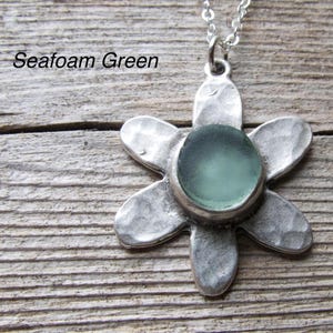 Handmade sea glass flower pendant necklace with aqua blue and other colours in a cabochon in a five-petal silver setting on a silver chain.