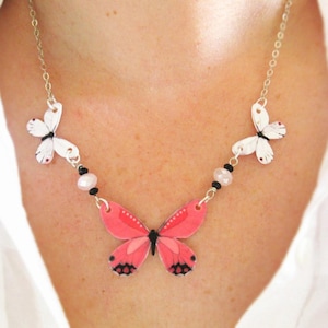 Pink butterfly pendant necklace, a delicate necklace, with white butterfly charms and a pink-and-black centerpiece.