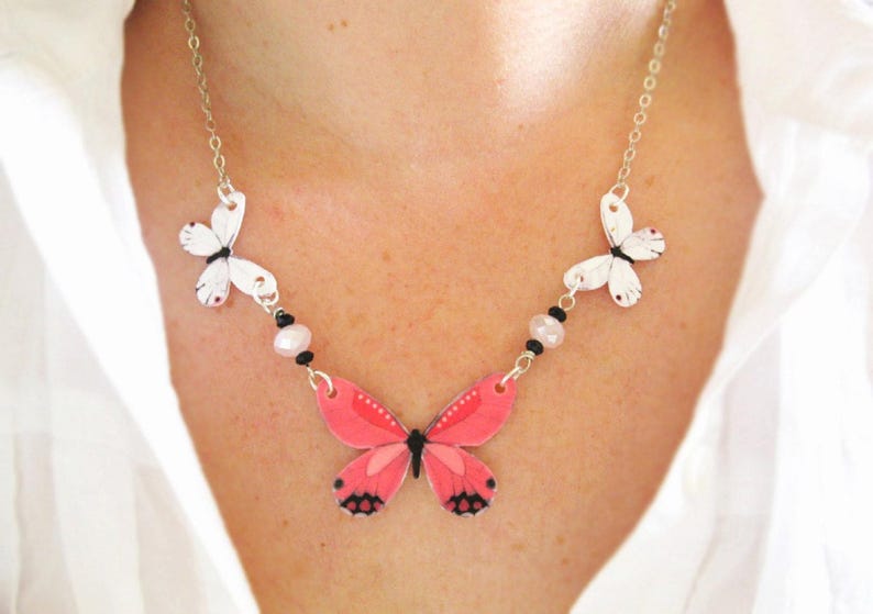 Pink butterfly pendant necklace, a delicate necklace, with white butterfly charms and a pink-and-black centerpiece.