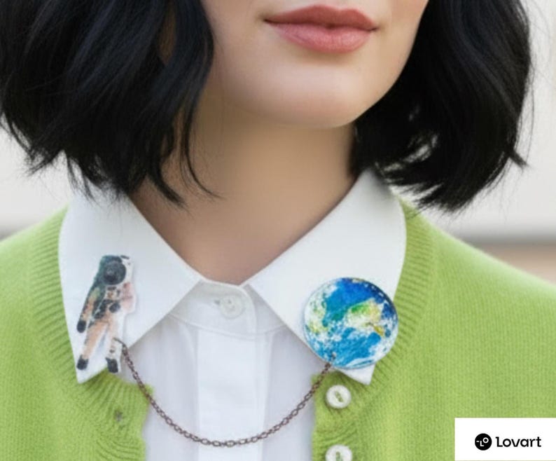 Astronaut pin with planet Earth pin linked by copper celestial chain on a white shirt collar — space pin duo.