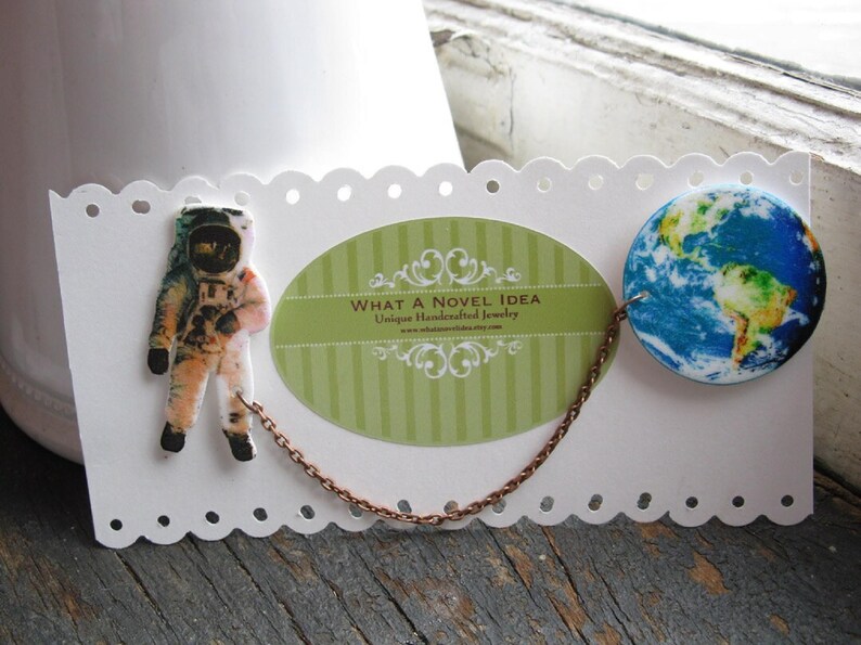 Astronaut and Earth globe double pin from outer space, linked by a celestial chain—space pin duo