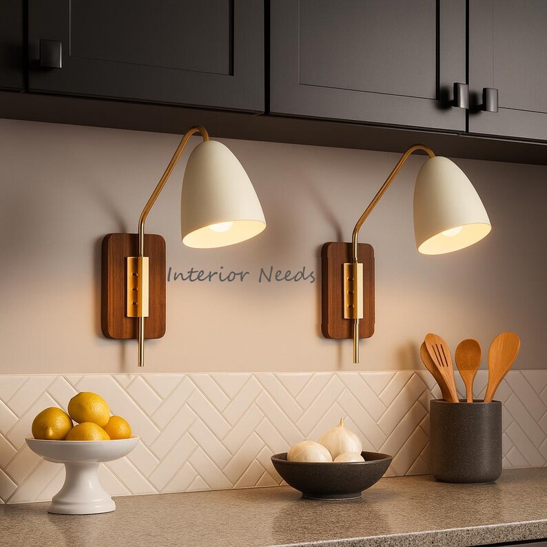 May include: Two wall sconces with white, cone-shaped shades and brass arms. They are mounted on rectangular wooden backplates. The image also shows a white ceramic fruit bowl with lemons, a black bowl with garlic, and a grey utensil holder.