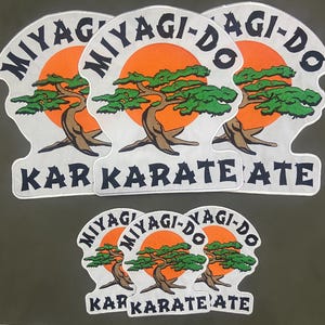 May include: A collection of Miyagi-Do Karate patches. Each patch features a stylized bonsai tree in front of an orange sun, with the words "MIYAGI-DO" and "KARATE" in black lettering. The patches are white with black borders.