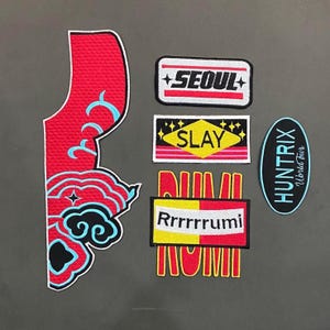 Könnte beinhalten: Eine Sammlung gestickter Aufnäher in verschiedenen Formen und Designs. Die Aufnäher zeigen Texte wie "SEOUL" und "SLAY" sowie dekorative Elemente in Rot, Gelb, Schwarz und Blau. Die Aufnäher sind wahrscheinlich für Kleidung oder Accessoires bestimmt.