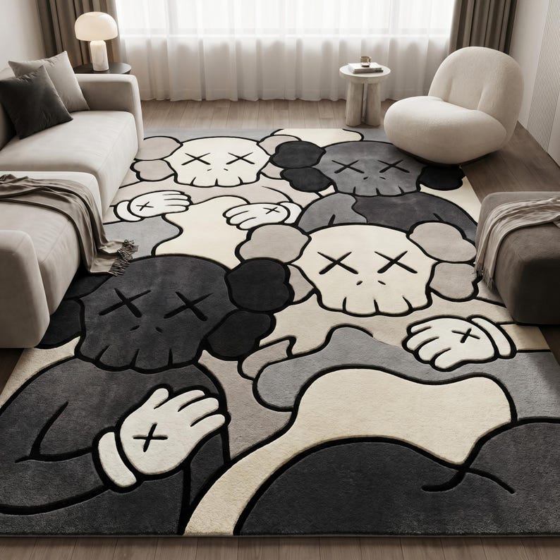 Striking modern rug in a minimalist living room. It features a dense wool texture and an abstract pattern of overlapping Kaws style companion figures with crossed eyes and gloved hands, rendered in rich shades of cream, light grey, dark grey, and black. The plush hand-carved design feels upscale and contemporary on a warm wood floor.
