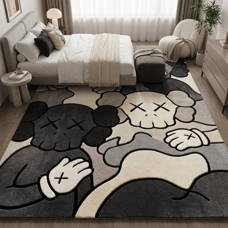 Striking modern rug in a minimalist living room. It features a dense wool texture and an abstract pattern of overlapping Kaws style companion figures with crossed eyes and gloved hands, rendered in rich shades of cream, light grey, dark grey, and black. The plush hand-carved design feels upscale and contemporary on a warm wood floor.