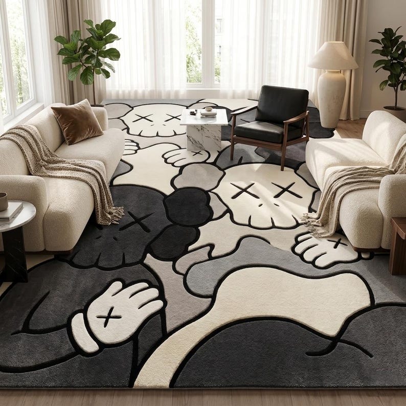 Striking modern rug in a minimalist living room. It features a dense wool texture and an abstract pattern of overlapping Kaws style companion figures with crossed eyes and gloved hands, rendered in rich shades of cream, light grey, dark grey, and black. The plush hand-carved design feels upscale and contemporary on a warm wood floor.