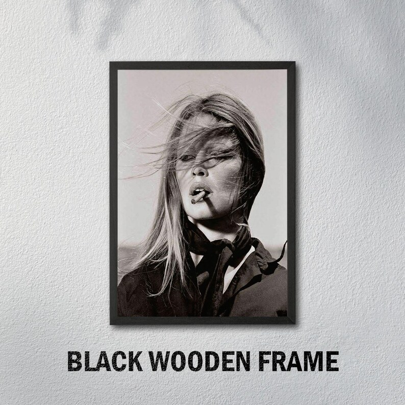 May include: Black and white framed print featuring a portrait of a woman with long hair, smoking a cigarette. The image is set against a neutral background and framed in a black wooden frame. The text "BLACK WOODEN FRAME" is at the bottom.