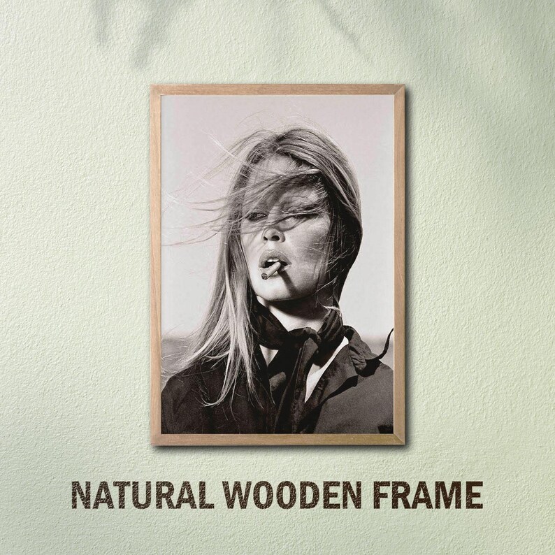 May include: Black and white framed print featuring a woman with wind-blown hair smoking a cigarette. The print is in a natural wooden frame. The text "NATURAL WOODEN FRAME" is printed at the bottom of the frame.