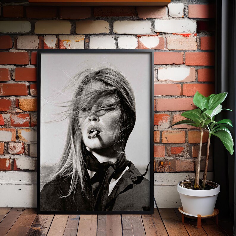 May include: Black and white framed portrait of a woman with long hair, smoking a cigarette. The image is a close-up, with the woman's face and upper body visible. She is wearing a dark top and a scarf.