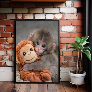 May include: A framed print featuring a baby monkey hugging a stuffed monkey. The baby monkey has gray fur and is embracing a plush toy with orange fur. The print is displayed against a brick wall, with a small potted plant nearby.
