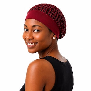 Op de afbeelding: Een bordeauxrood haarnetje met een bijpassende hoofdband. Het net is een gehaakt ontwerp. De hoofdband is effen van kleur. De persoon op de foto draagt een zwarte tanktop en een pareloorbellen.