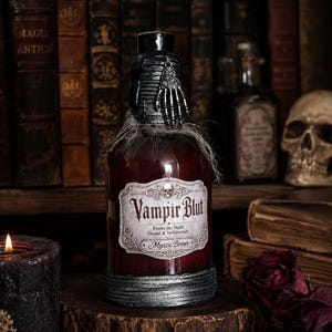 Könnte beinhalten: Eine dunkelrote Glasflasche mit schwarzem Verschluss und einem silbernen Skeletthand-Anhänger. Das Etikett zeigt ein Totenkopf-Symbol und den Text "Vampir Blut, Essenz der Nacht, Dunkel & Verführerisch, Mystic Brews." Der Boden ist schwarz umrandet.