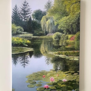 Puede incluir: Una pintura de paisaje enmarcada representa una serena escena de estanque. La obra de arte presenta una masa de agua reflectante con nenúfares y nenúfares rosas. Frondosos árboles y follaje verde rodean el estanque, creando un ambiente tranquilo y natural.