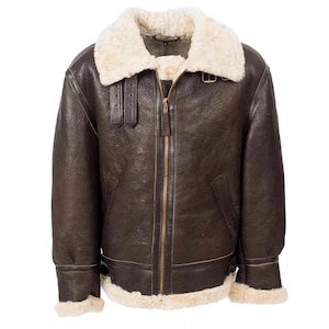 Peut inclure: Veste en cuir marron avec col et doublure en peau de mouton crème. La veste est dotée d'une fermeture éclair sur le devant, de deux poches latérales et de sangles réglables aux poignets. Style aviateur classique.