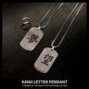 May include: Two silver dog tag pendants with Japanese Kanji characters for "dream" and "hope" on a chain. A silver ring is also present. The text "KANJI LETTER PENDANT" and "A SERIES OF THE MOST POPULAR KANJI LETTER" is at the bottom.