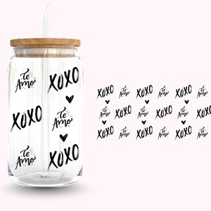 Pu&ograve; includere: Un bicchiere di vetro trasparente con coperchio in legno e cannuccia bianca. Il bicchiere &egrave; decorato con le parole "XOXO" e "Te Amo" in grafia nera, insieme a piccoli cuori neri. Il disegno si ripete su sfondo rosa.