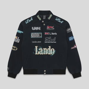 Puede incluir: Chaqueta de carreras azul marino con múltiples parches y textos bordados. La chaqueta presenta el nombre "Lando" en una fuente cursiva en el pecho, junto con varios logotipos y el texto "L. Norris" y "Lando Norris Racing Team".