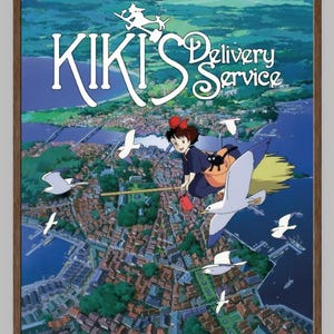 K&ouml;nnte beinhalten: Ein gerahmtes Poster des Animationsfilms "Kikis kleiner Lieferservice". Es zeigt eine junge Hexe auf einem Besen &uuml;ber einer K&uuml;stenstadt fliegend. Der Titel ist in Wei&szlig; dargestellt. Die Szene spielt vor blauem Himmel und Meer, mit M&ouml;wen.